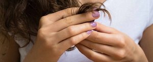 Brunette woman examining the ends of her hair