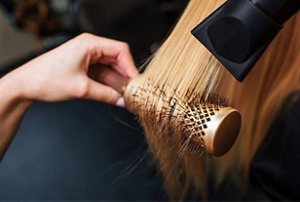 Woman having her hair styled with a rounded brush and a hairdryer