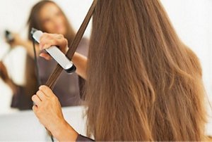 Woman straightening her hair in front of a mirror