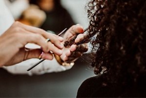 Woman with dense coily hair having her hair cut by a stylist