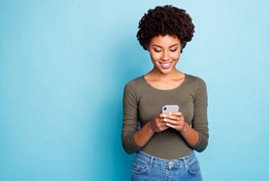 Smiling woman using her mobile phone against a blue background