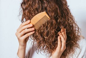 Woman carefully running a wide-toothed comb through her damp curly hair