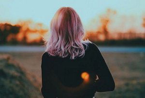 Woman with pastel pink hair walking outside