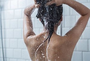 Woman washing her hair with a frizz-fighting shampoo