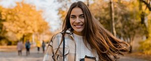Smiling woman outside on an autumn day with long, frizz-free hair