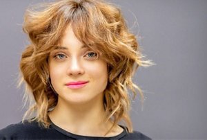 Woman wearing pink lipstick with a shaggy auburn wolf cut