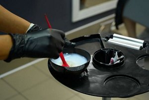 Stylist mixing hair tint in a black plastic bowl