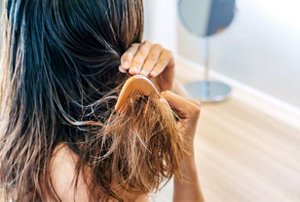 Woman roughly combing her hair with a wooden comb