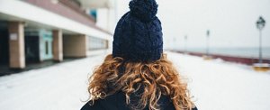 Woman wearing a navy blue bobble hat while walking through the snow