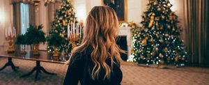 Young woman with long, rich auburn hair looking at a Christmas tree