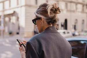 Professional woman with her hair in a low bun texting as she walks