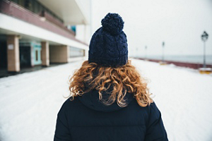 Redheaded woman wearing a bobblehat walking in snow
