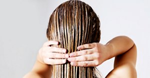 Woman applying hair conditioner. Isolated on white.