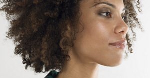 Closeup of a young afro woman with curly hair against white background