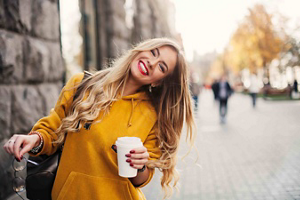 Smiling young woman with long blonde hair holding a cup of coffee