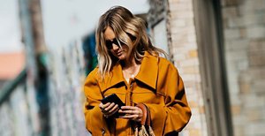Woman with mid-length blonde wavy hair looking at her phone