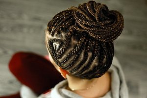 African braids are gathered in the tail with a pattern from the cornrow on the temple, an original youth hairstyle