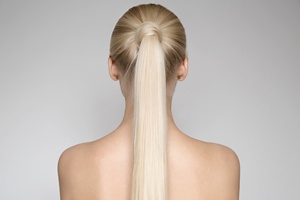 Woman with long blonde hair wearing it in a topknot