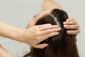 Woman smoothing a serum through her lengths and onto her scalp