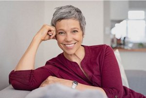 woman with short greys sitting on sofa and smiling to camera