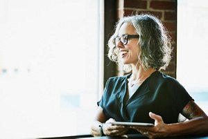 smiling woman with medium grey hair wearing glasses