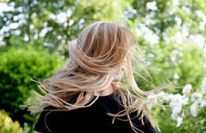 Woman in a black t-shirt flipping her highlighted blonde hair