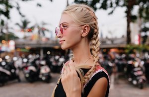 Blonde woman tying back her longer fringe into braids