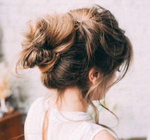 Bridesmaid with her hair styled into a structured messy bun with free-flowing tendrils