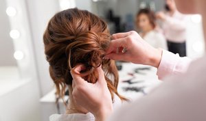 Bridesmaid having her hair styled into a twisted low updo