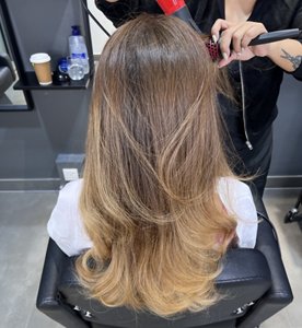 Woman with brunette ombre having a butterfly cut styled at the hairdressers
