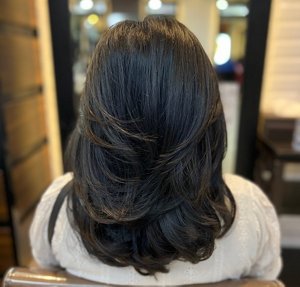 Young woman with dark brunette hair styled in a voluminous butterfly cut