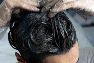 Woman applying dark hair dye to her lengths