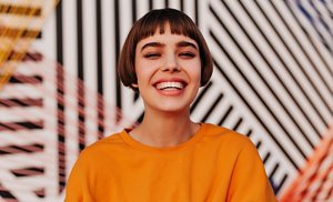 Woman wearing an orange jumper with a French bob with a micro fringe