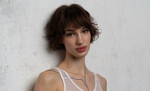 Young woman with a short French bob hairstyle wearing a white mesh top