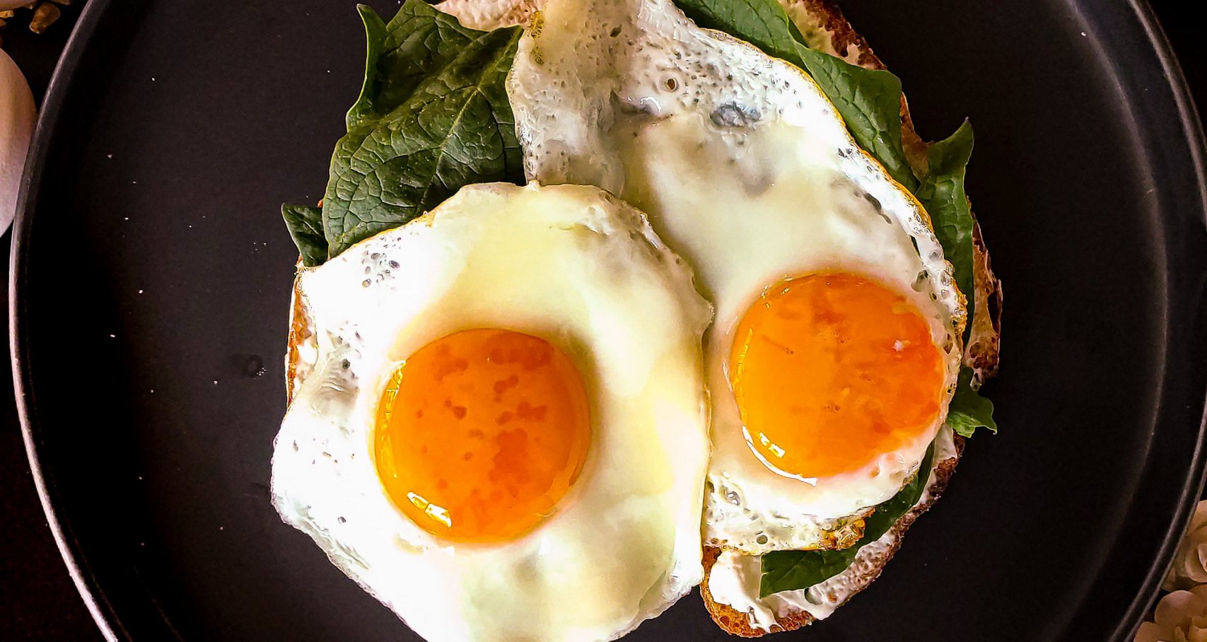 Fried eggs and spinach on a grey plate