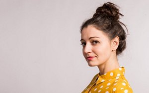 Young woman wearing a yellow polka dot blouse with her hair in a top knot