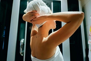 Woman wrapping a white towel around her damp hair