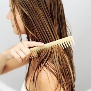 Woman combing serum through wet hair