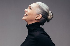 Happy older woman with natural grey hair tied up in a bun