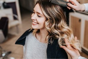 Woman with long, wavy brunette hair with caramel highlights
