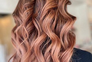 Woman with long, wavy balayage on red hair