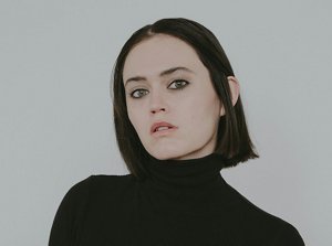 Young woman wearing a back polo neck top with a blunt hime haircut