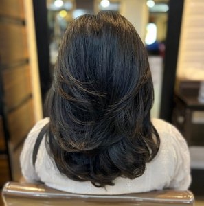 Woman with long black hair styled into soft, fluffy layers