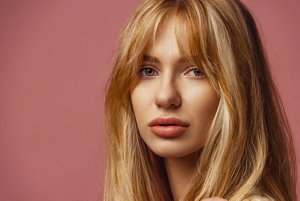 Woman with strawberry blonde hair with a long fringe