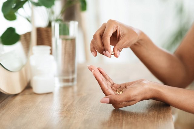 Lady with a pink manicure adding supplements to her outstretched hand
