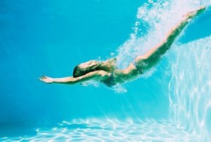 Woman with long blonde hair diving into a swimming pool