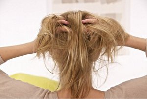 Woman holding her fine, thin blonde hair