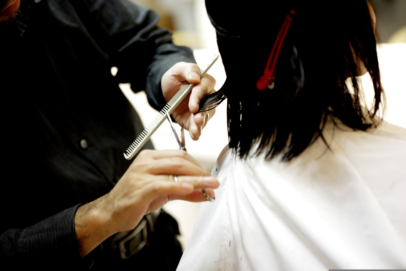Woman with dark hair getting a trim in the hairdresser