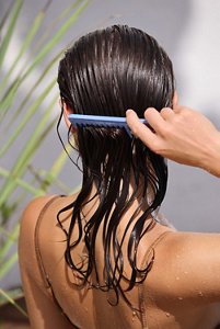 Woman brushing an oil-based product through wet, curly hair