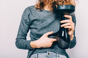 Woman in a grey top using a diffuser to dry her hair